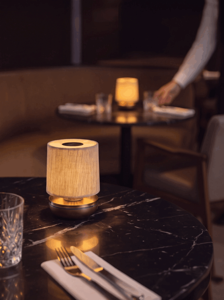 Humble Firefly Akku-Tischleuchte auf Marmortisch im Restaurant